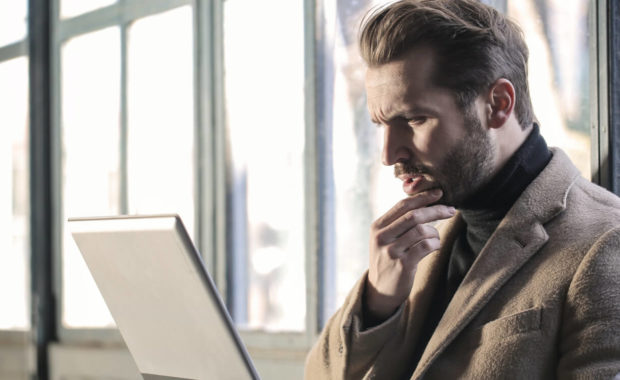 man with laptop thinking about coinbase vs binance